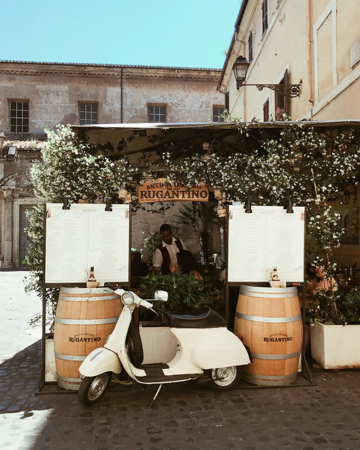 Un motorino bianco d'epoca parcheggiato davanti a un ristorante italiano.