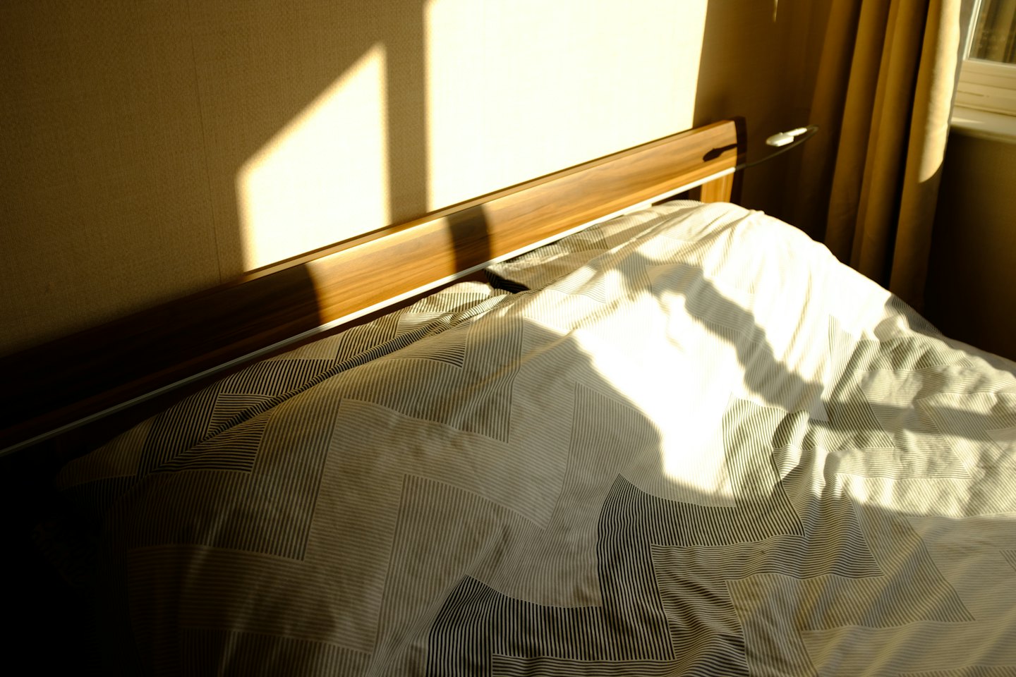 La luce del sole filtra su un letto con un copriletto fantasia.